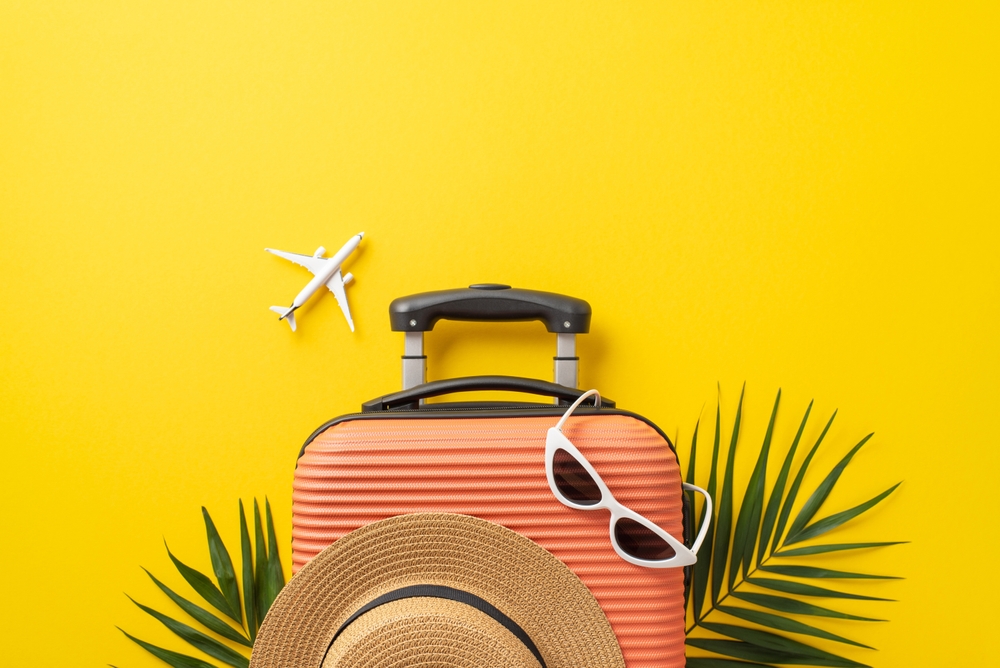 suitcase and sunglasses against yellow background